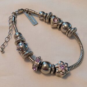 Elegant charm bracelet. Silver Tone With Pink Zirconia Accents.